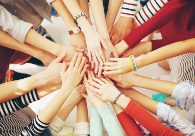 Image of people touching hands in the middle of a circle